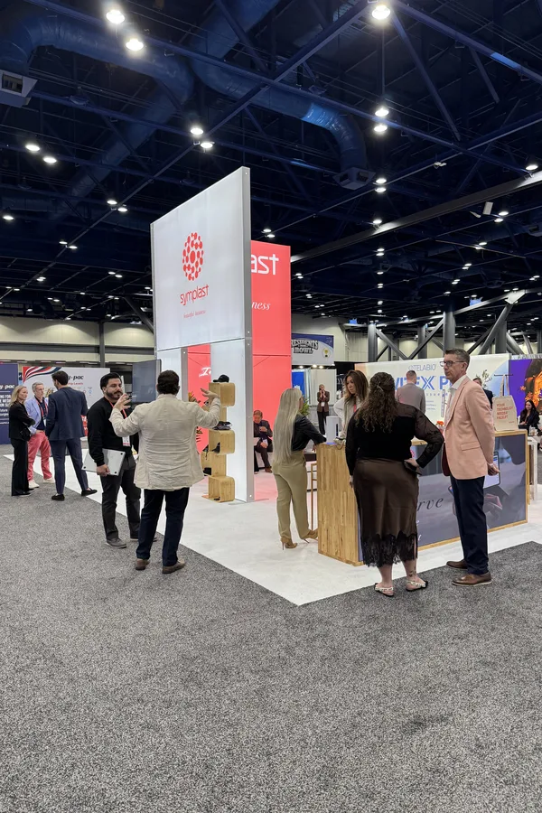 Attendees talking at the Symplast booth on the PSTM 2026 exhibit floor